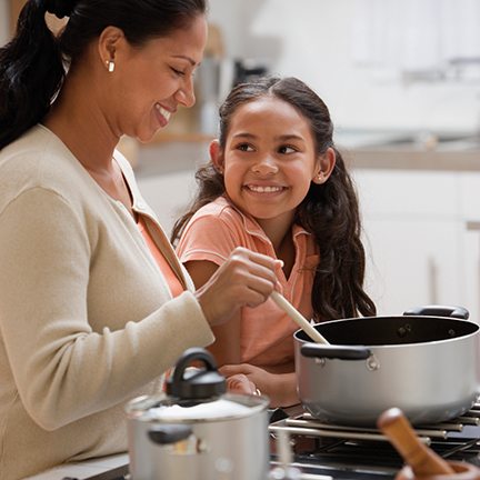Mother teaching daughter the importance of cooking and eating vegetables with everyday meals.