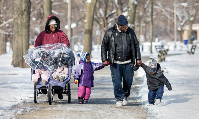 African American Family Walking in Winter Snow During Holiday Season