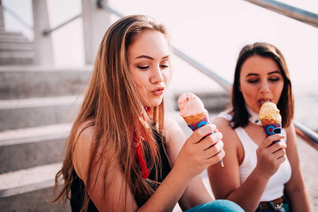 Young Women Indulging in Eating Ice Cream on the Beach After Her Exercise